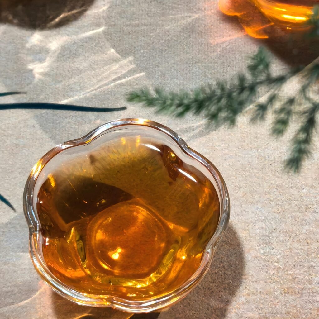 Steaming glass cup filled with golden amber Jin Mu Dan oolong tea.