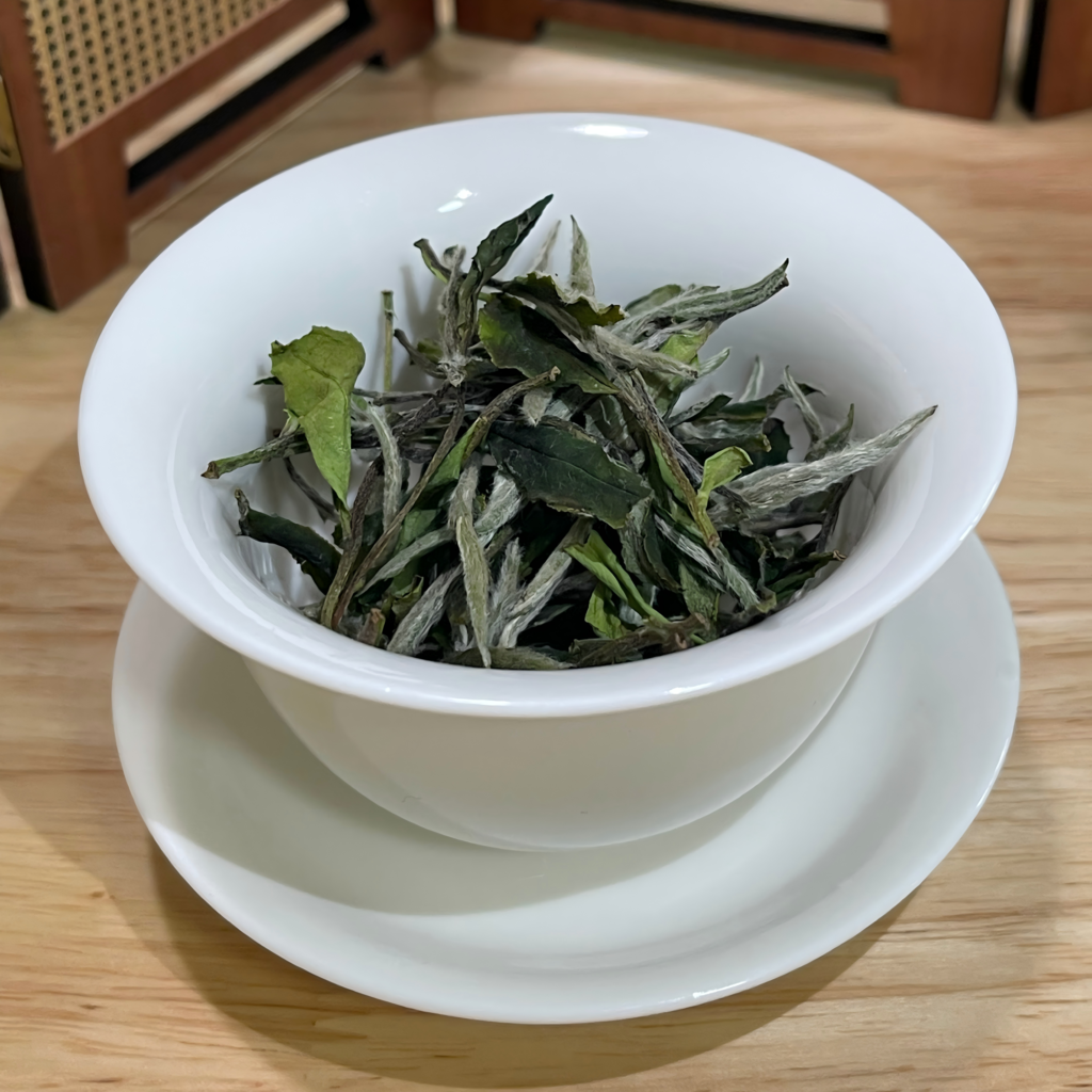 White Peony tea being poured from a Chinese gaiwan into a small tasting cup