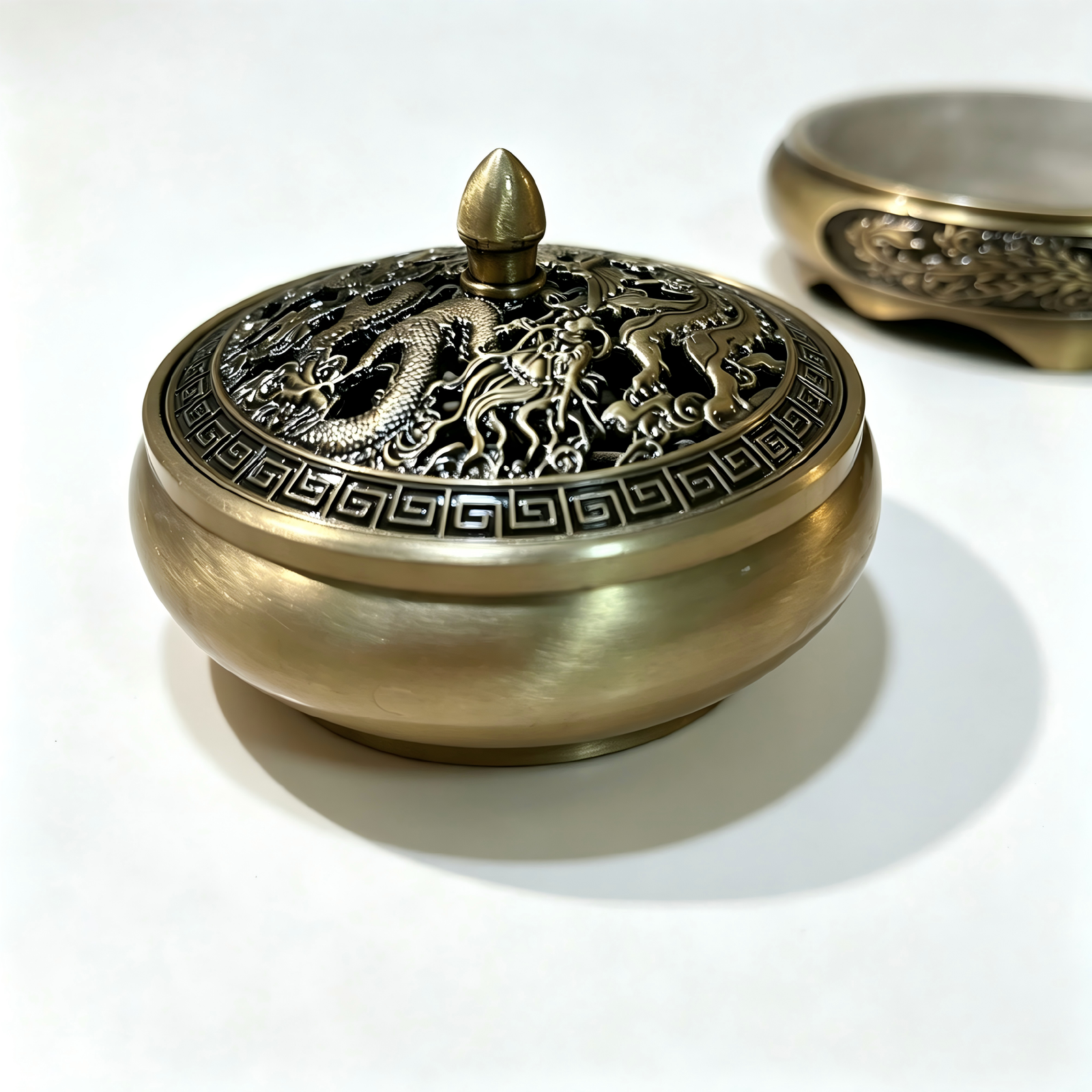 Close-up detail of a Chinese traditional incense burner showing hand-burnished Dragon and Phoenix motifs with a high-contrast blackened relief patina.