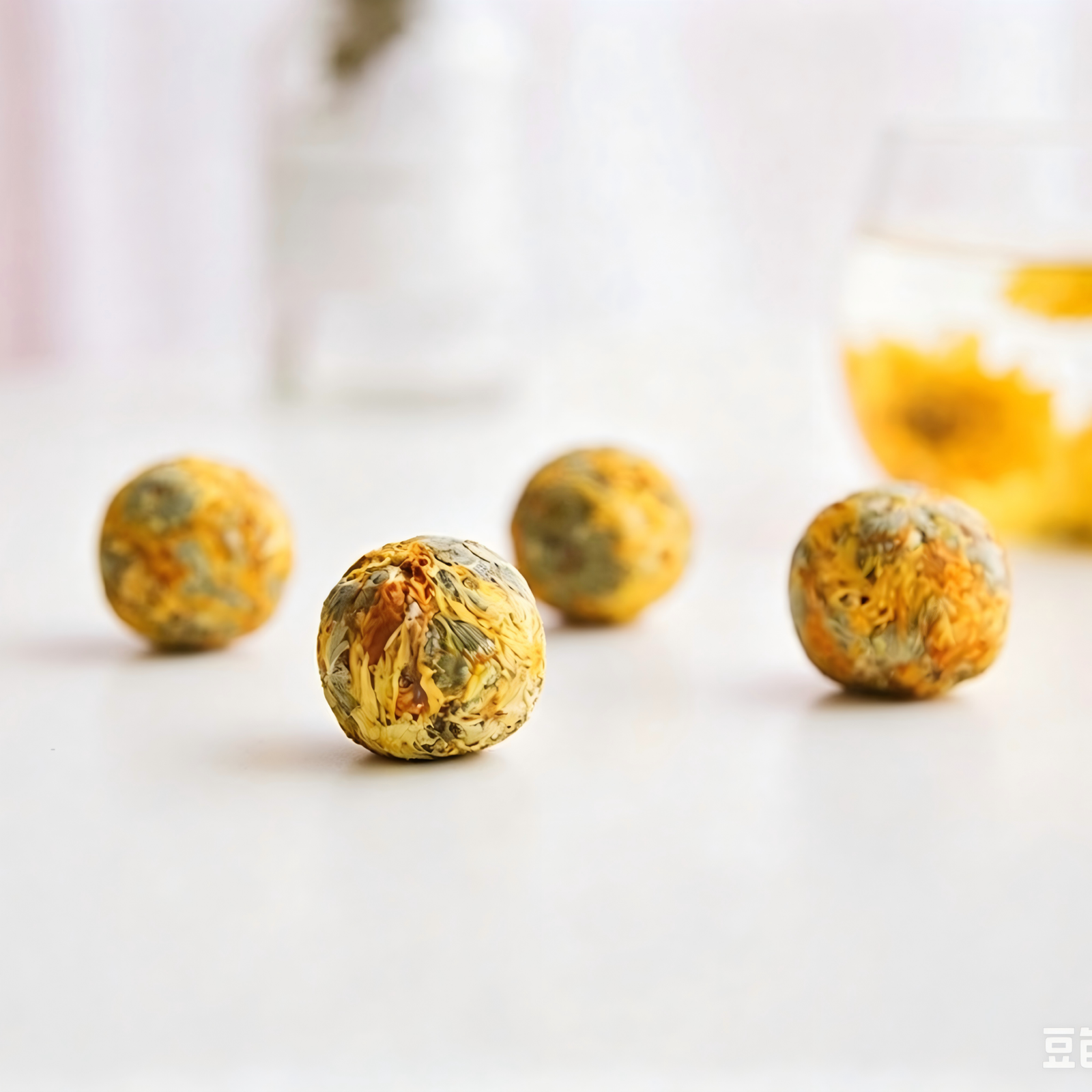 A single Golden Silk Chrysanthemum tea dragon ball unfurling into a large yellow blossom in a glass teapot.
