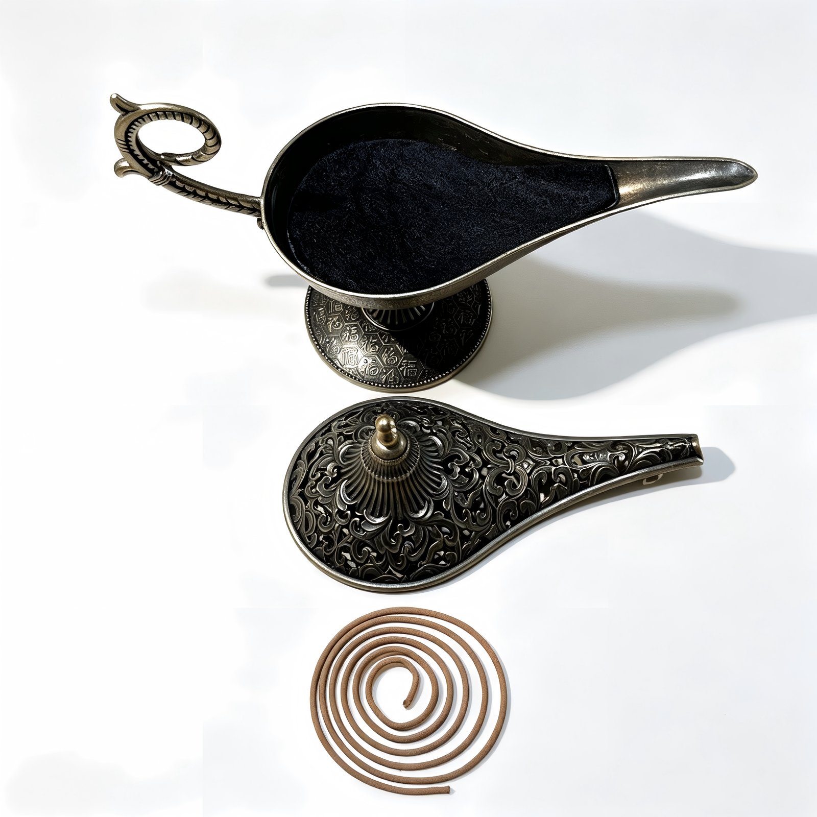 An overhead exploded view of the antique bronze Aladdin lamp incense burner, showcasing the open ash basin layered with fine black incense sand, the detached intricate filigree lid, and a natural brown coil incense beneath on a pure white background.