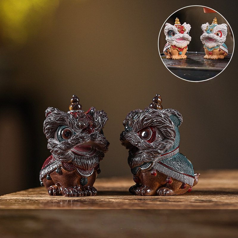 Two traditional Chinese lion dance tea pets in their dark, dormant room temperature state on a wooden gongfu tea table