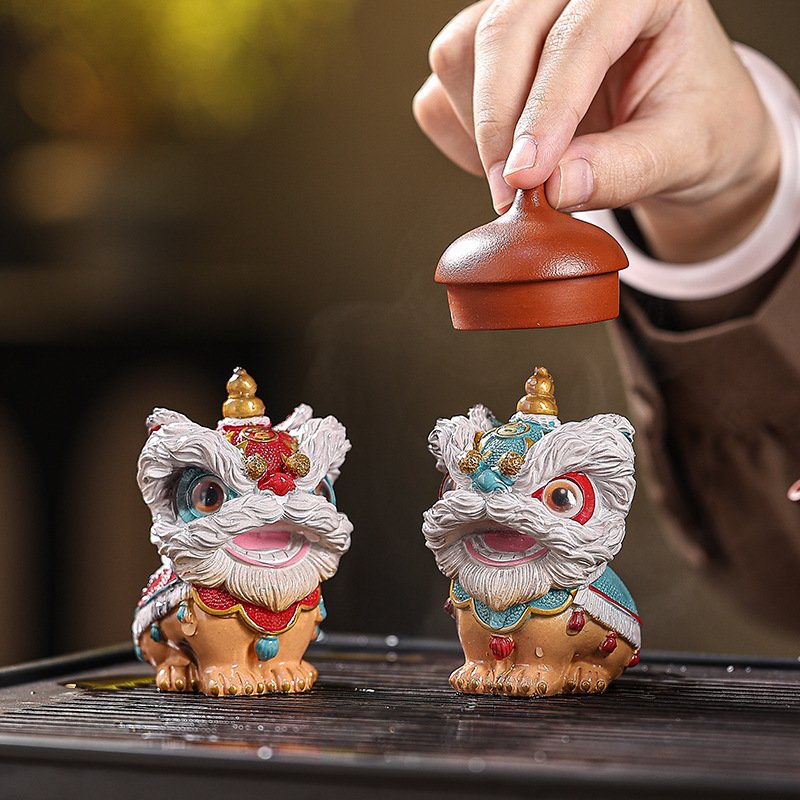wo pieces of a gongfu tea pet set displaying both the dark dormant state and the vibrant awakened colorful state on a wet tea tray