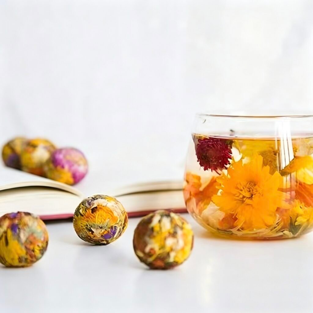 Vibrant Hundred Flowers herbal tea blend blooming in a glass teapot