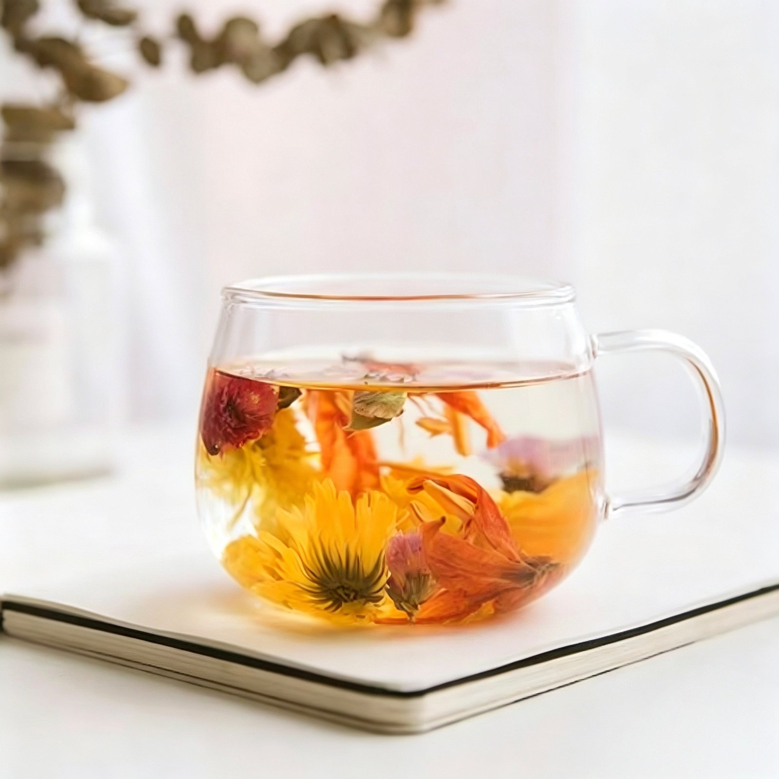 Vibrant Hundred Flowers herbal tea blend blooming in a glass teapot