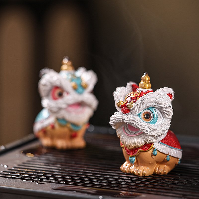 A pair of temperature-sensitive tea ornaments featuring the traditional Chinese lion dance motif with steam rising in the background