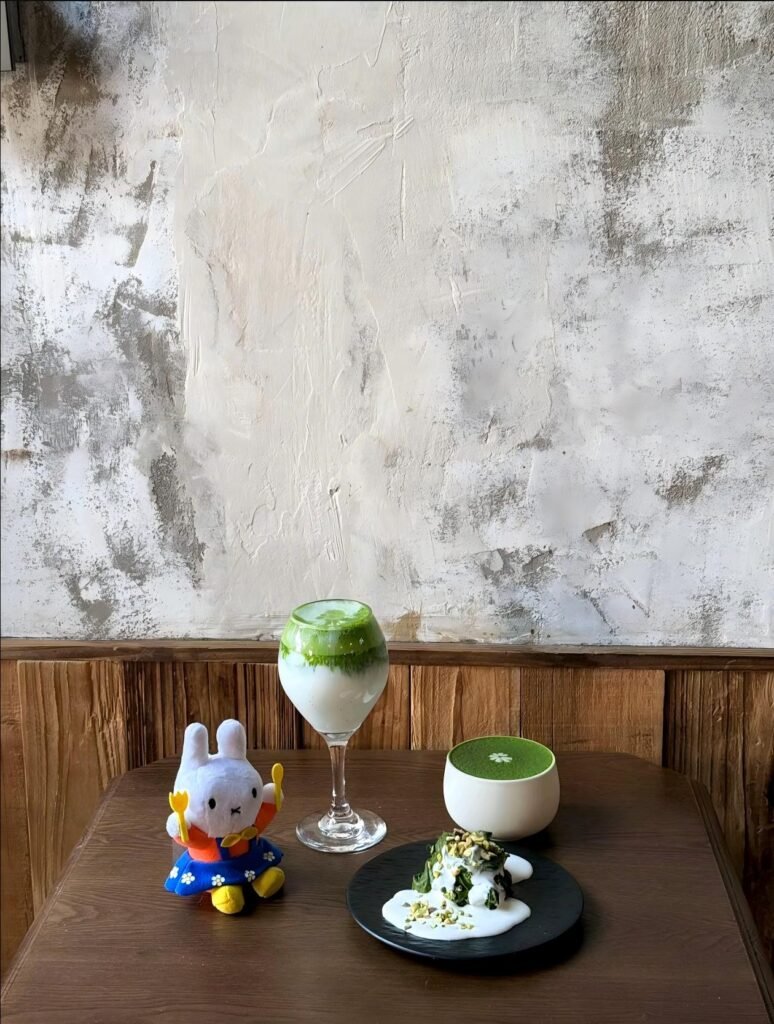 A modern cafe display of matcha desserts including latte, cake, and ice cream in signature jade green