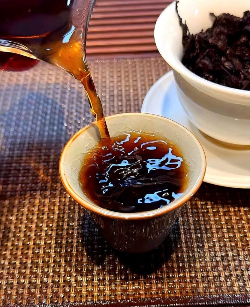 Gongfu brewing of 2021 Lincang aged Shou Puerh Tuocha in porcelain gaiwan showing deep ruby red liquor