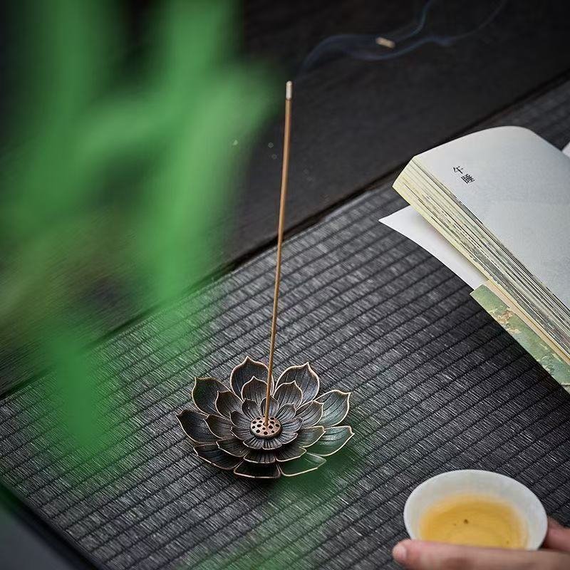 Three-layer lotus incense holder in antique bronze sitting on a wooden desk