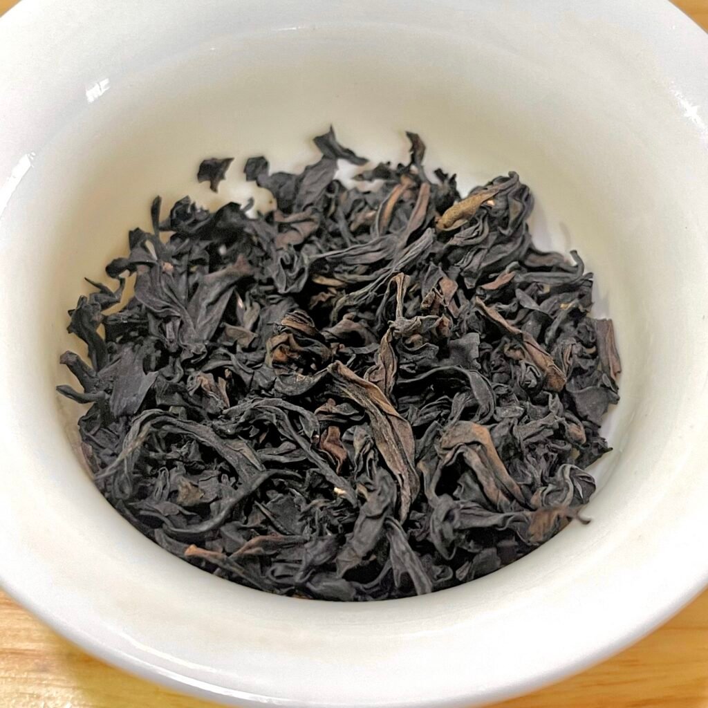 Dry leaves of Wuyi cinnamon rock tea showing twisted, dark roast strips.