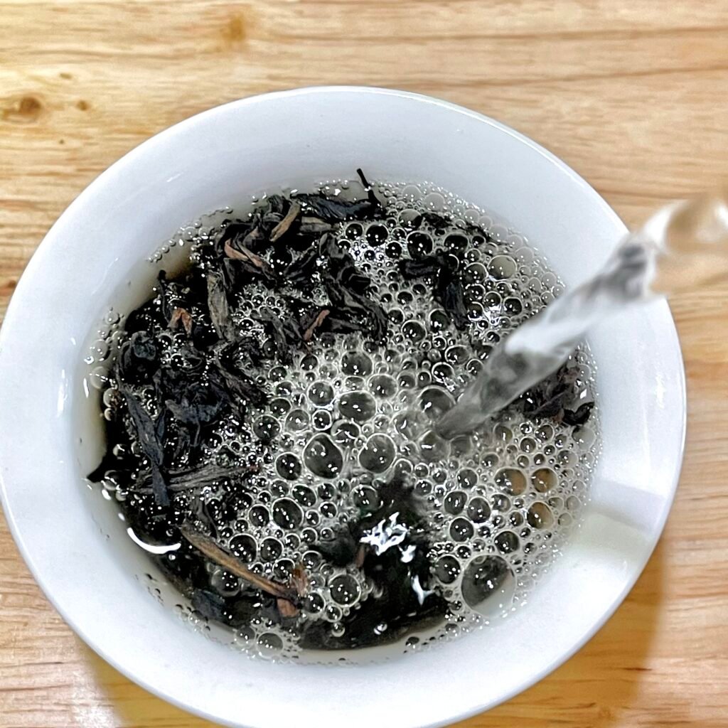 Properly brewed Wuyi rock tea in a white porcelain cup showing translucent amber liquor that indicates good quality